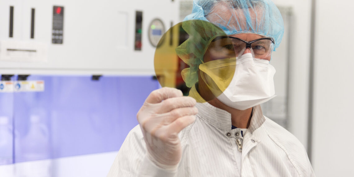 A scientist at SK Siltron CSS holds a silicon carbide wafer produced at the company's Michigan facility