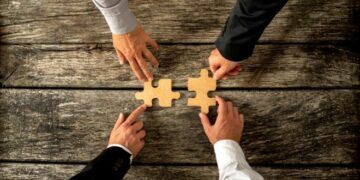 four hands with two puzzle pieces